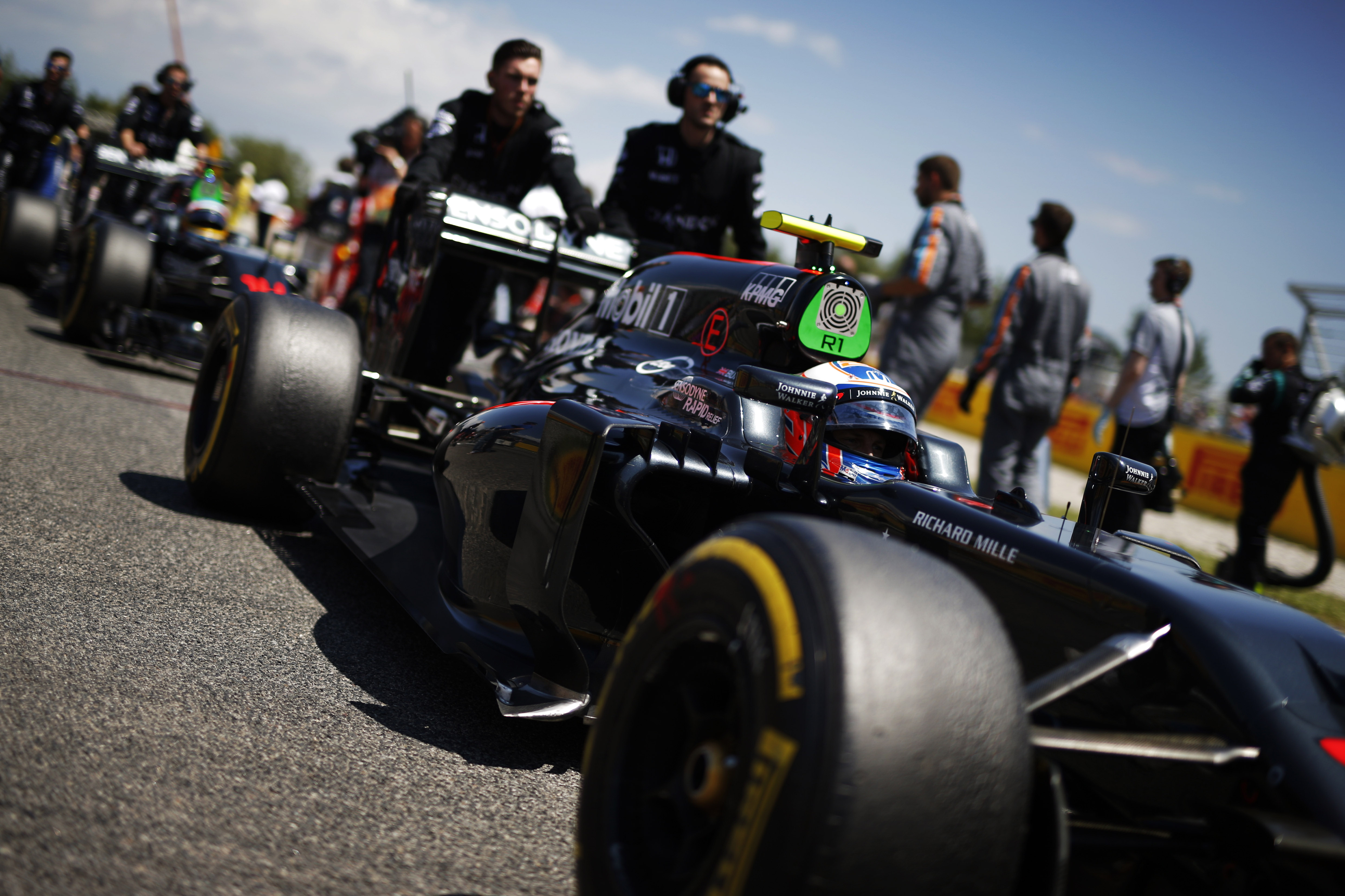 Jenson Button is pushed onto the grid by team members ahead of Fernando Alonso.